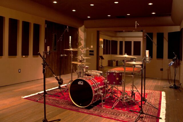 Red drum set in recording studio with black acoustic panels on walls behind